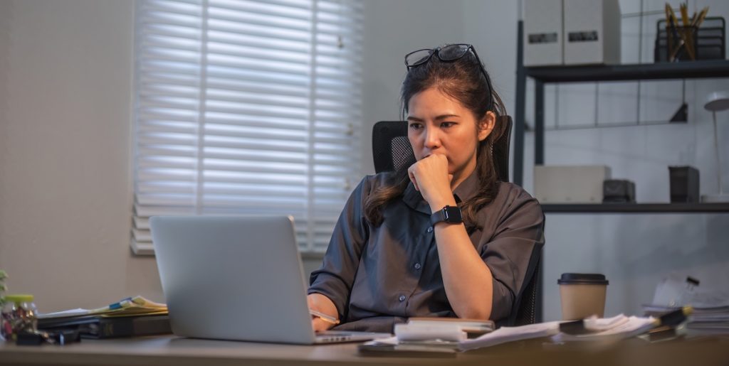 Puzzled confused asian woman thinking hard concerned about online problem solution looking at laptop screen.