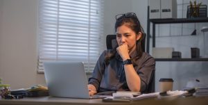 Puzzled confused asian woman thinking hard concerned about online problem solution looking at laptop screen.