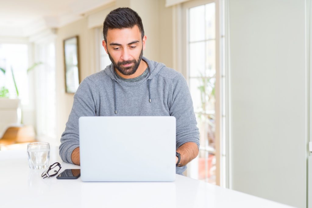 Handsome hispanic man working using computer laptop with a confident expression on smart face thinking serious