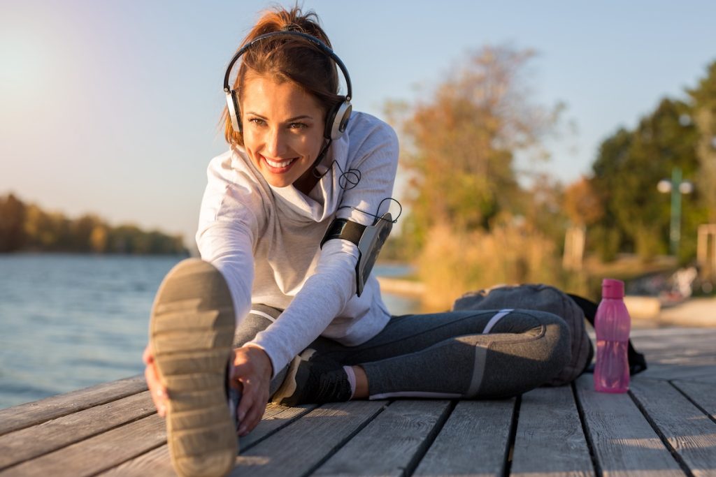Beautiful young woman working out outside by the water while smiling